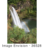 #36528 Stock Photo Of The Wailua Falls Flowing Over The Cliffs Into The Pool Below Its Mist Creating A Rainbow Kauai Hawaii