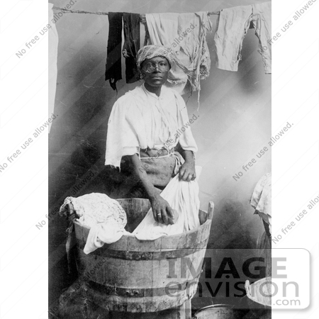 #27641 Stock Photo of a West Indian Woman Standing In Front Of A Half Barrel, Pulling Out Washed Laundry And Hanging Them To Dry On A Clothes Line by JVPD
