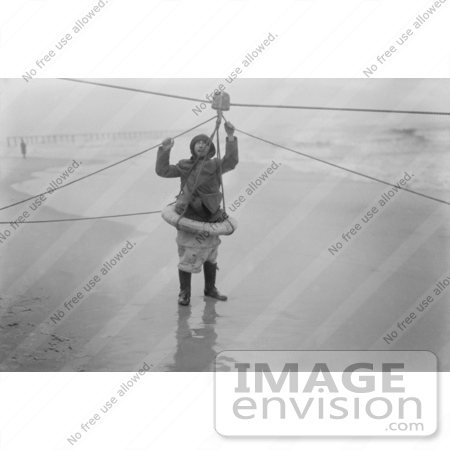 #35642 Stock Photo Of A Man Standing On A Beach And Demonstrating A Ship Rescue Apparatus With A Pulley And Lifesaver Ring by JVPD