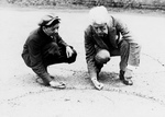 Man Showing a Boy How to Shoot Marbles