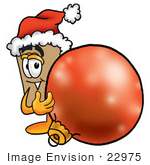 #22975 Clip Art Graphic Of A Cardboard Shipping Box Cartoon Character Wearing A Santa Hat Standing With A Christmas Bauble