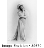 #35670 Stock Photo Of A Beautiful Woman, Broadway Actress Julia Marlowe, Standing, Wearing A Hat And Dress And Touching Her Face While Looking Off To The Right by JVPD