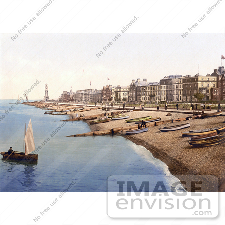 #26847 Stock Photography of a Man Rowing a Boat Near a Beach With Boats Lined up on the Shore and Waterfront Buildings in Herne Bay Kent South East England by JVPD