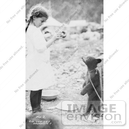 #27890 Historical Stock Photo of a Litte Girl Holding Up A Donut To A Hungry Bear Cub That Is Standing On Its Hind Legs And Tied By A Chain by JVPD