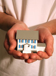 Man Holding a Model House in His Hands