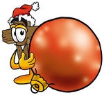 Clip Art Graphic of a Wooden Cross Cartoon Character Wearing a Santa Hat, Standing With a Christmas Bauble